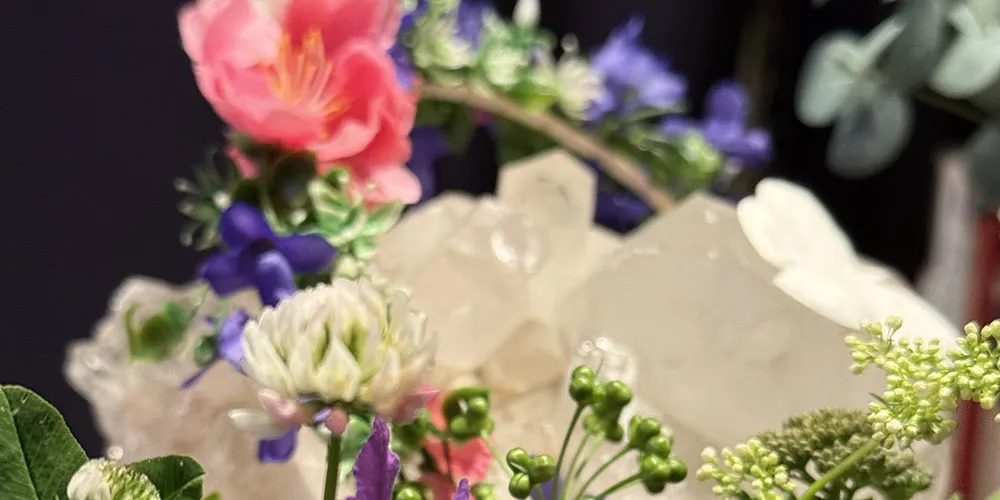 Erivärisiä kukkia ja taka-alalla vaalea iso kristalli